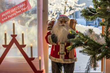 Karlı villa kapısında Noel ağacı, İsveç mum tutacağı ve penceresinde 