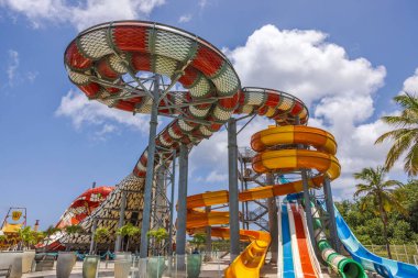 Güneşli gökyüzünün altında, bulutlu ve palmiye ağaçlı renkli tüplü su parkı. Willemstad. Curacao.