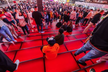 Times Meydanı, New York 'taki kalabalık kırmızı basamakların güzel manzarası, insanların yürüdüğü ve oturduğu, gece şehrin canlı enerjisini yakaladığı. - New York. ABD.