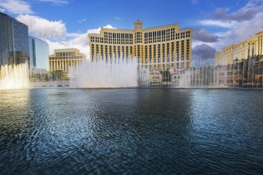 Beautiful view of fountain show in front of Bellagio hotel casino with cloudy blue sky in Las Vegas. Nevada. USA.  clipart