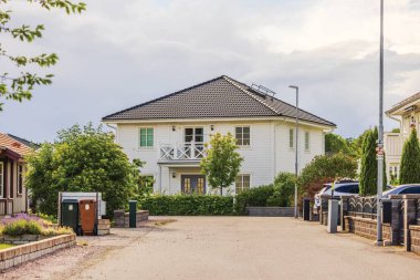İsveç mahallesinde ağaçlar ve bitkiler olan sessiz bir yerleşim yerindeki modern beyaz villa..