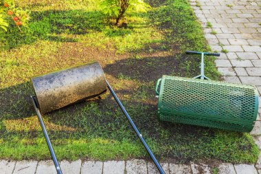 Bahçedeki toprağı düzleştirmek ve sıkıştırmak için geleneksel çim silindiri ve elek toprak silindirinin yakın görüntüsü. İsveç.