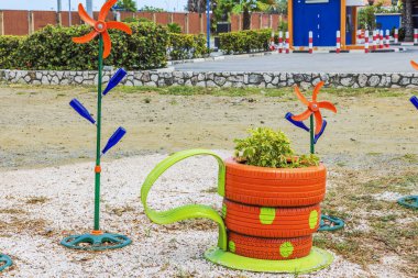 Beautiful view of creative outdoor garden decoration featuring colorful recycled tires as planters and bottle wind spinners in vibrant park setting. Curacao. clipart