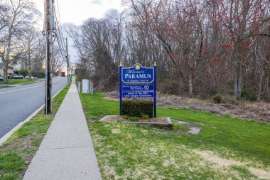 New Jersey 'deki ilkbahar sokağındaki Paramus tabelasına hoş geldiniz. Asfalt yolu, villalar, park edilmiş arabalar ve çıplak ağaçlar. New Jersey, ABD. 