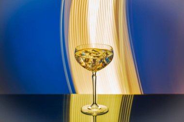 Soyut arkaplana buz küpleriyle birlikte bardağa dökülen martininin yakın görüntüsü.