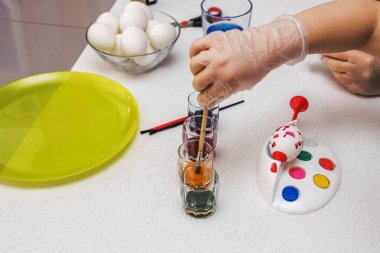 Yaratıcı ev aktiviteleri sırasında Paskalya yumurtalarını parlak renklerle boyayan çocukların yakın çekimi. İsveç.