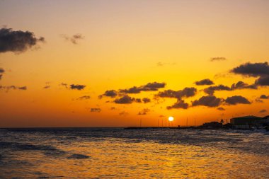 Curacao adasındaki Karayip Denizi 'nin üzerinde güzel bir gün batımı. Bulutlar suya altın ışığı yansıtıyor..