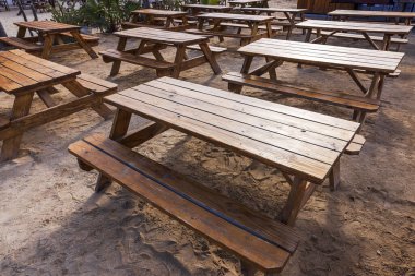 Kumlu zemine yerleştirilmiş ahşap piknik masaları, Curacao Adası 'ndaki sahil bölgesinde yemek ya da dinlenme için açık hava restoranına kurulmuş..