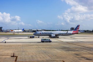 American Airlines plane on tarmac at Miami International Airport, with ground crew and vehicles in clear sunny weather. Miami. USA.  clipart