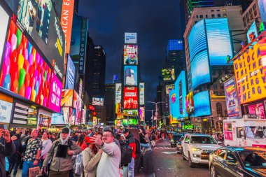 Tourists taking selfies in Times Square at night, surrounded by bright billboards, traffic, and vibrant city lights. New York. USA. clipart