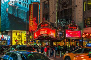 Aydınlanmış Hard Rock Cafe 'nin önünde gece kalabalık toplandı ve New York' ta kalabalık caddelerden arabalar geçti. ABD.