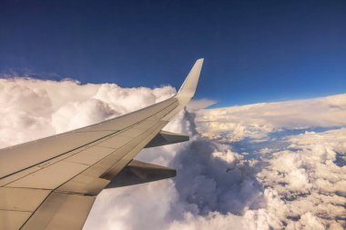 Bulutların üstünde uçarken kanat manzarası açık mavi gökyüzünde bulutlarla.