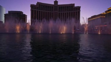 Las Vegas 'taki Bellagio Fountains' in akşam manzarası. Aydınlatılmış su jetleri Bellagio Hotel 'in arka planına karşı senkronize bir gösteri sergiliyor. Las Vegas mı? ABD. 