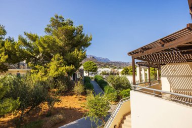 Yunanistan 'ın Girit adasındaki ağaçlar, patikalar ve uzak dağlarla güneşli Akdeniz tatil beldesi.