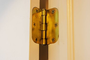 Pirinç kapı menteşesinin beyaz kapı çerçeveli yakın görüntüsü.