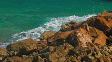 Turkuaz Karayip Denizi 'nin kayalara çarpan dalgaların yavaş çekimleri su sıçratan ve engebeli taş dokuları gösteriyor. Curacao.