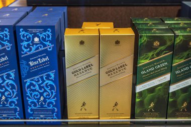 Johnnie Walker Blue Label, Gold Label Reserve ve Ada Yeşil Viskiler düzgünce rafa dizilmiş. 