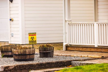 Warning sign 'Beware of Zombies' in yard near planters, Halloween decoration in front of house. Sweden. clipart