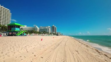 Miami, Florida 'da güneşli bir günde cankurtaran istasyonu, şemsiyeleri ve açık mavi gökyüzü altında otelleri olan kumsal. Miami Plajı. ABD. 
