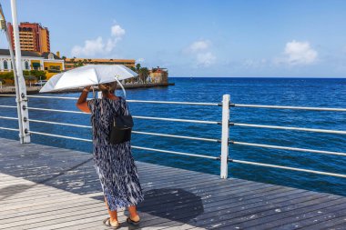 Willemstad, Curacao 'daki St. Anna Körfezi üzerindeki Kraliçe Emma Pontoon Köprüsü' nde UV şemsiyeli kadın.. 