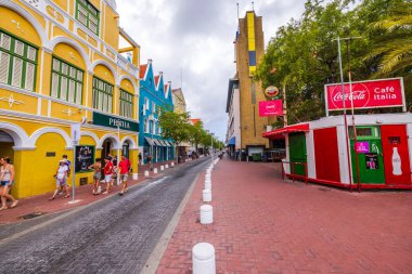 Willemstad 'daki renkli binalar ve sokak kafeleri bulutlu bir günde gezinen insanlarla dolu.. 