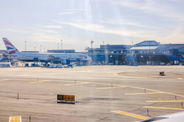 İngiliz Havayolları uçağı güneşli bir günde yer ekibi ve ekipmanlarıyla havaalanı kapısında. - New York. ABD. 