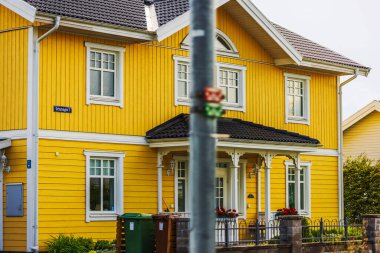 Banliyöde beyaz süslemeli ve küçük bahçeli parlak sarı ahşap villa.