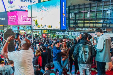 New York City 'de kalabalık bir turist topluluğu selfie ve fotoğraf çekiyor. Geceleri etrafında canlı reklam panoları var. - New York. ABD. 