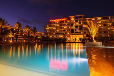 Curacao 'daki Corendon Oteli' nin gece manzarası. Parlayan ışıklar, palmiye ağaçları ve havuz yansımaları huzurlu bir atmosfer yaratıyor.. 