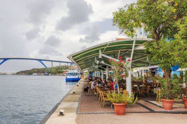 Willemstad, Curacao 'daki Anna Körfezi' nde, Kraliçe Emma Köprüsü 'nün yanında tepe örtüsü altında turistlerin bulunduğu açık deniz yemekhanesi.. 