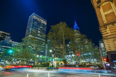 Manhattan 'daki Bryant Park' ın gece görüşü. Şehir ışıkları, yüksek binalar ve geçen araba farlarının ışık yolları. ABD.