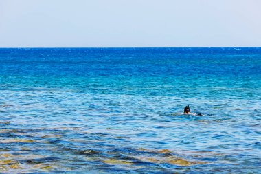 Yunanistan 'ın Rodos adasında, açık Ege Denizi' nde, parlak yaz güneşi altında şnorkelle yüzen kişi.