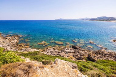 Rodos adasında güneşli gökyüzünün altında Ege Denizi 'nin turkuaz sularıyla kayalık kıyı şeridi..