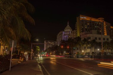 Royal Palm Hotel 'in yer aldığı Miami' deki Collins Caddesi 'nin gece manzarası hareket halindeki arabaların ışık yolları ve bulanık detaylar. Miami Plajı. ABD. 