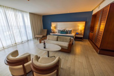 Meksika 'da modern ahşap mobilyalar, rahat koltuklar, büyük yatak ve doğal ışıklandırma içeren zarif bir otel odası. Cancun. Meksika. 