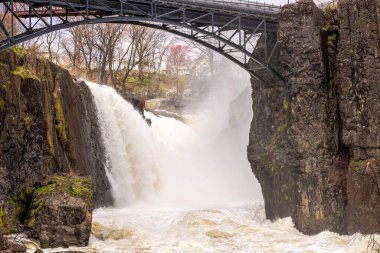 Paterson, New Jersey 'deki kayalık uçurumlar arasında şelale gibi akan güçlü bir köprü. ABD.