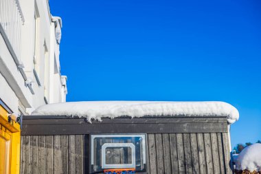 Çatı altındaki koyu ahşap duvara bağlı basketbol potası canlı mavi kış gökyüzüne karşı karla kaplıydı. İsveç.