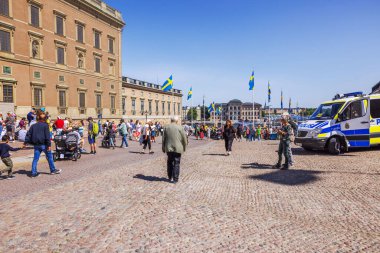 İsveç Ulusal Günü 'nü İsveç bayrakları, tarihi mimari ve polis varlığıyla kutlayan kalabalık meydanda. 