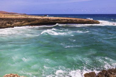 Dalgalar, Arikok Ulusal Parkı, Aruba 'da turkuaz su ile kayalık sahil şeridine çarpıyor..