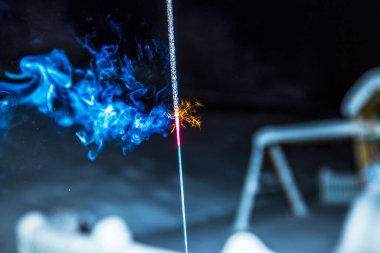 Işıldayan turuncu kıvılcımlar saçan parlak mavi kıvılcımlar karanlık kış gecelerinde karlı arka planda parlıyordu. İsveç.