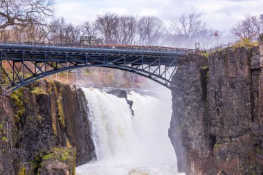 Great Falls şelalesi ve çelik kemer köprüsü Paterson, New Jersey 'deki sisli bahar manzarasıyla çevrili..