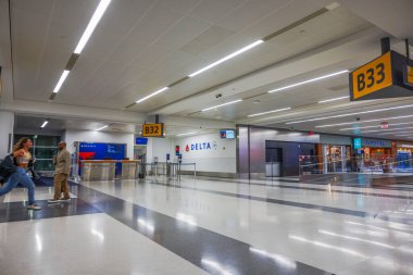 Delta Havayolları, Newark Liberty Uluslararası Havaalanı 'nın B32 ve B33 numaralı kapılarında uçağa yetişmek için koşan bir kadınla birlikte. New Jersey, ABD. 