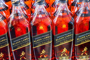 Johnnie Walker 'ın yakın plan görüntüsü Black Label harmanlanmış viski şişeleri ve rafta kırmızı yansımalar var.. 