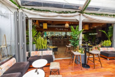 Modern çatı barı, tropikal bitkiler, şık koltuklar ve cam çatı altında şehrin ufuk çizgisine bakan açık iç tasarım. - New York. ABD. 