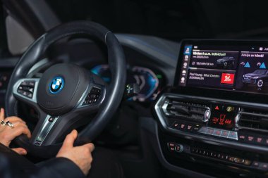 Interior of BMW iX3 electric car showing illuminated steering wheel controls, digital dashboard and advanced infotainment system display at night.  clipart