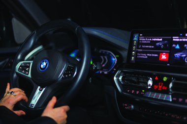 Woman drives BMW iX3 electric car at night with an illuminated dashboard and digital display.  clipart