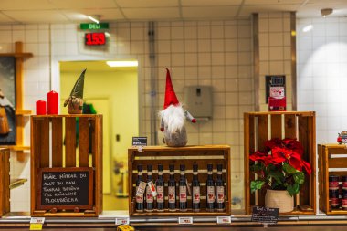 Şarap şişeleri, noktalı çiçekler, mumlar ve Noel cücesi heykelcikleri sergilenen ahşap sandıklarla süslenmiş market tezgahı.. 