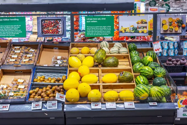 Taze kavunlar, karpuzlar ve marketteki meyve raflarındaki ahşap sandıklarda sergilenen kiviler.. 
