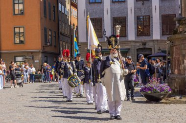 İsveç Ulusal Günü 'nde Kraliyet Sarayı yakınlarındaki meydanda yürüyen tarihi askeri üniformalar ve İsveç bayraklarıyla geçit töreni..