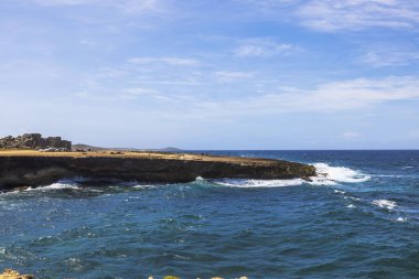 Aruba 'daki Arikok Ulusal Parkı' nın Rocky kıyı şeridi. Turkuaz Karayip Denizi dalgaları tarihi altın kalhanesi kalıntılarının yakınına çarpıyor..